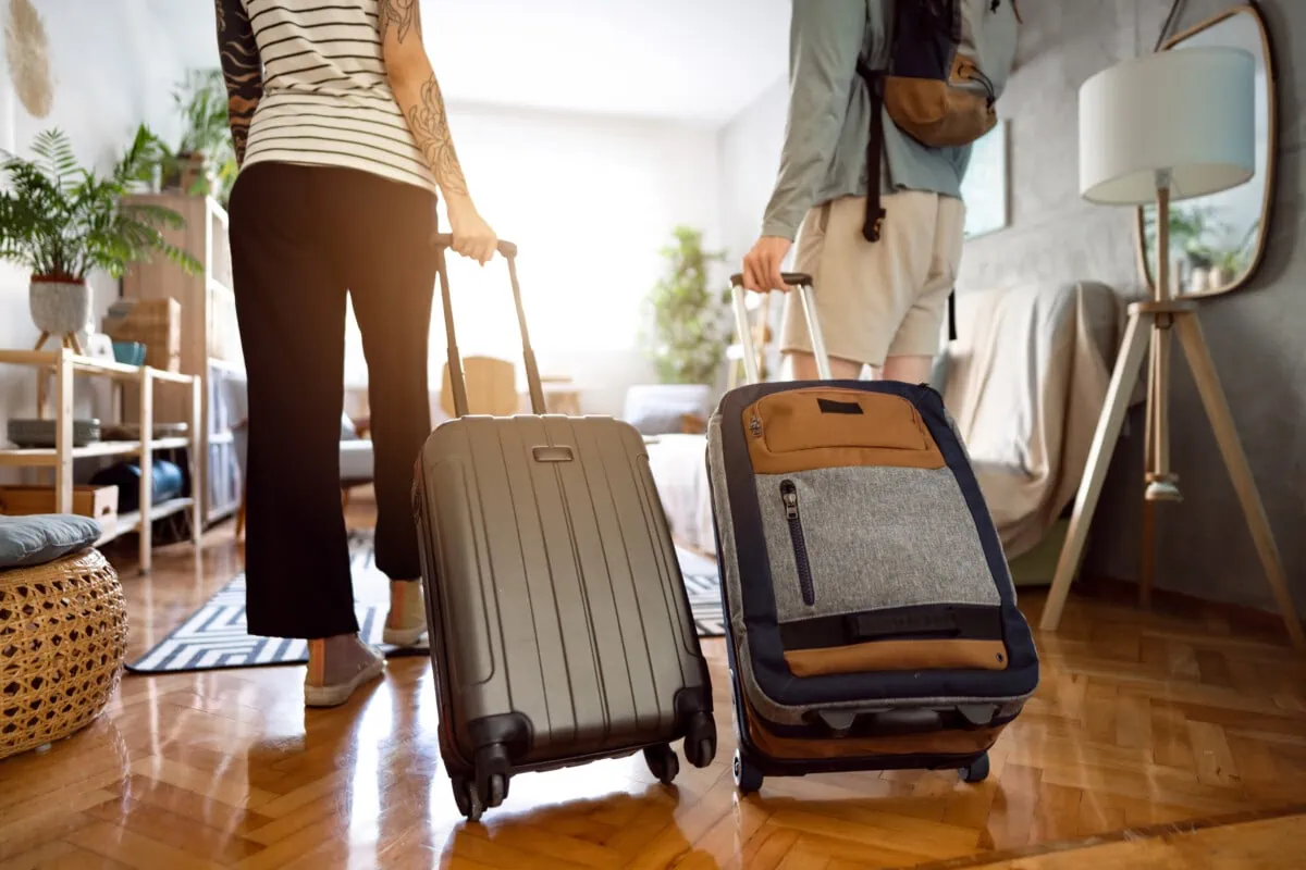 Two people walking with luggage in a living room, showcased on a website created using Webflow for marketing purposes.